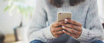 close up of woman holding phone in both hands 