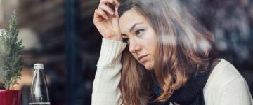 Photo of a woman looking stressed, resting her head in her hand